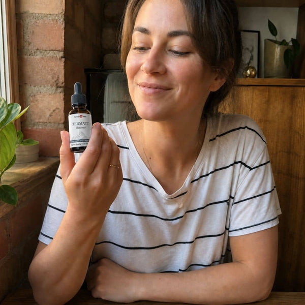 Donna che tiene una bottiglia di olio di CBD Zermatt in un ambiente interno accogliente.
